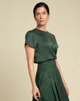 Woman wearing a green Silk Lotus T-shirt and Silk/cotton Skirt outfit by daniel 
Gonzalez Designs against a beige background
