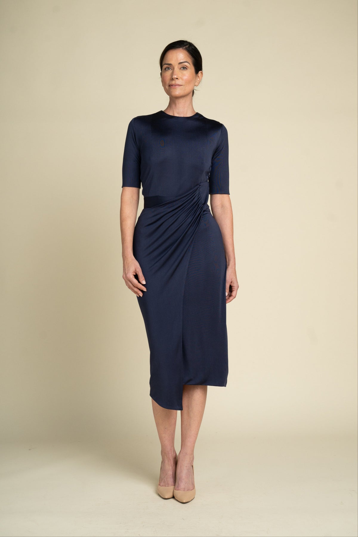 Woman wearing a navy blue dress against a beige background